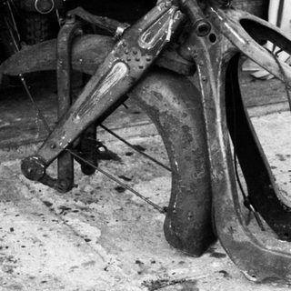 Destroyed motorcycle frame on workshop floor.