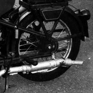 Person riding vintage motorcycle on road.