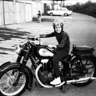 Person riding vintage motorcycle on road.