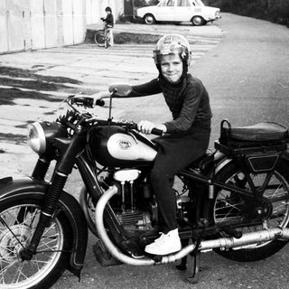 Person riding vintage motorcycle on road.