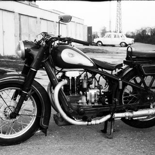 Classic black-and-white motorcycle with sidecar, parked outdoors.