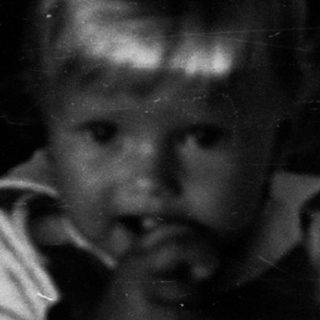 Young child peering through crib bars.