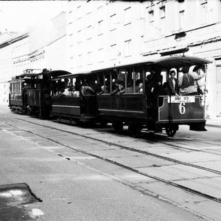 Vintage tram with passengers on city street.