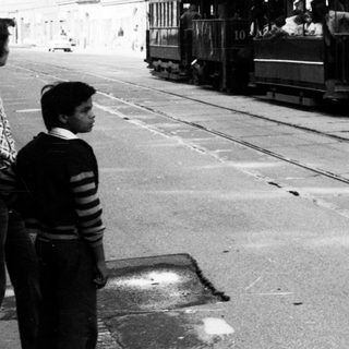 Vintage tram with passengers on city street.
