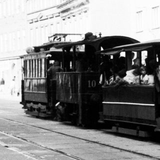 Vintage tram with passengers on city street.