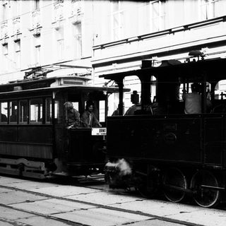 Vintage tram with steam locomotive in city.