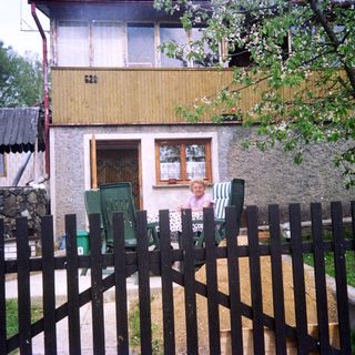 Rural house with child sitting by fence.