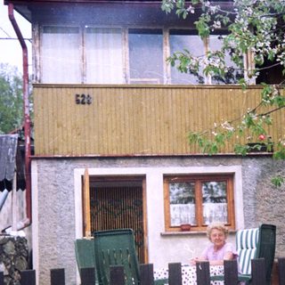 Rural house with child sitting by fence.