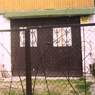 Two-story yellow and white building with gated entrance.