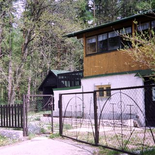 Rural house surrounded by forest with gated driveway.