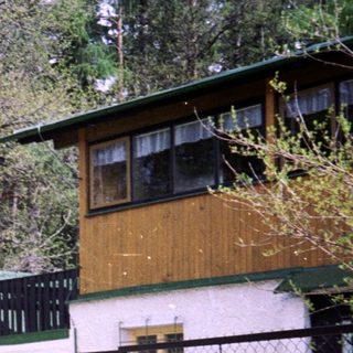 Rural house surrounded by forest with gated driveway.