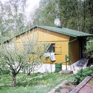 Rural wooden cabin with person walking dog outside.