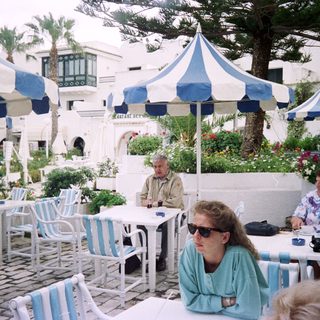 Outdoor café with people seated under striped umbrellas.