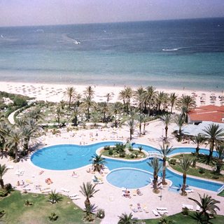 Luxury resort with pools, beach, and palm trees.