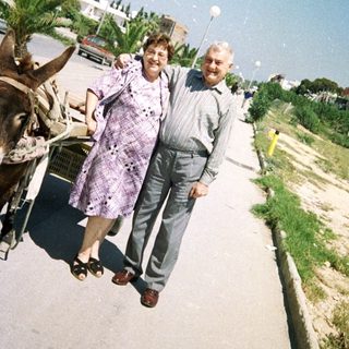 Two people walking beside a donkey cart outdoors.