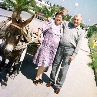 Two people walking beside a donkey cart outdoors.