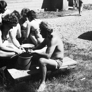 Group of people playing with bucket outdoors.