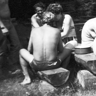 Group of people sitting around a fire pit outdoors.