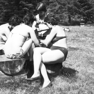 Group of people sitting around a fire pit outdoors.