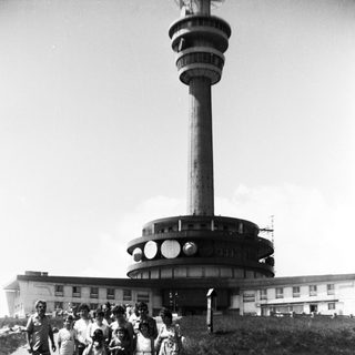Group posing near tall observation tower.