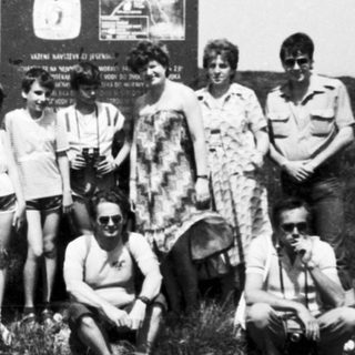 Group of people posing outdoors near sign reading "Vrchol Pradědu."