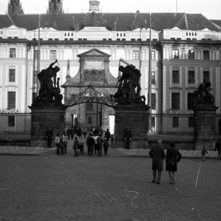 Historic gate with statues, grand building, and courtyard.