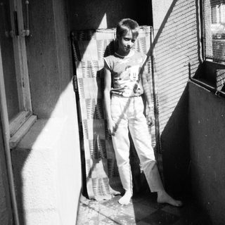 Young boy holding tennis racket in indoor hallway.