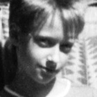 Young boy holding tennis racket in indoor hallway.