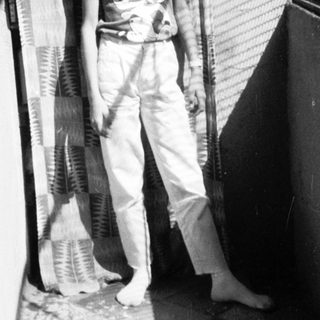 Young boy holding tennis racket in indoor hallway.