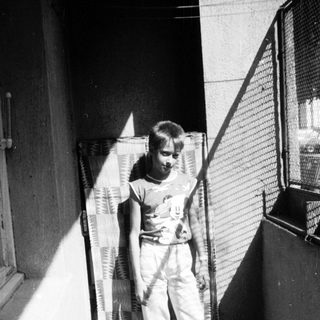 Young boy holding tennis racket in indoor hallway.