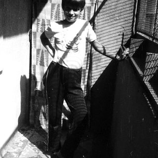 Young boy playing guitar outdoors on stairs.