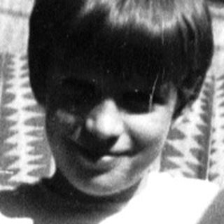 Young boy playing guitar outdoors on stairs.