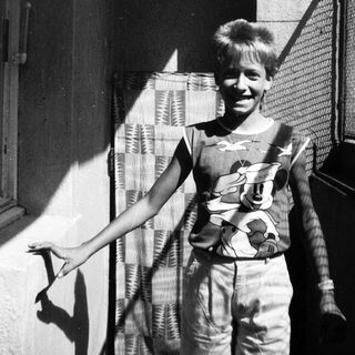 Young boy smiling outside near window.