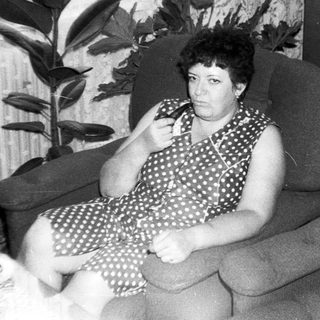 Woman sitting on sofa indoors, holding phone.