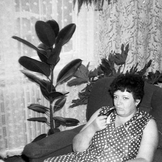Woman sitting on sofa indoors, holding phone.