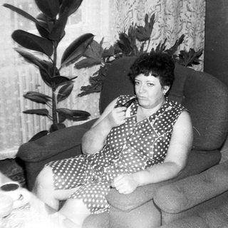 Woman sitting on sofa indoors, holding phone.