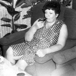 Woman sitting on armchair eating, indoors.