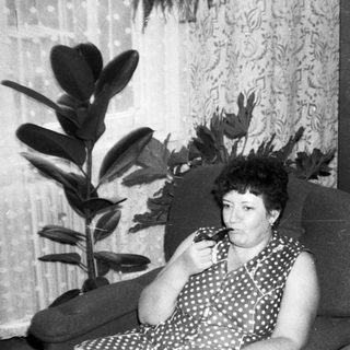 Woman sitting on armchair eating, indoors.
