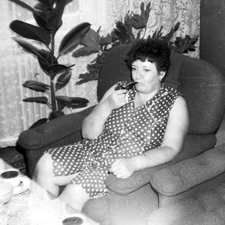 Woman sitting on armchair eating, indoors.