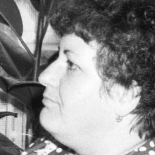 Woman resting on couch with plant beside her.