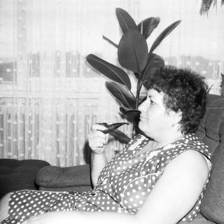 Woman resting on couch with plant beside her.