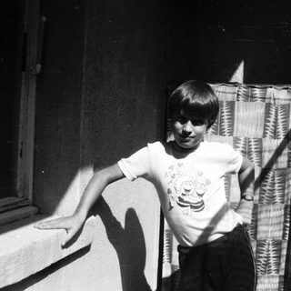 Young boy smiling near open window.
