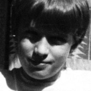 Young boy smiling near open window.
