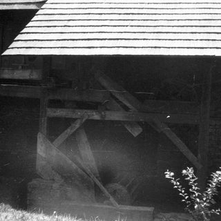 Old wooden barn with slanted roof and open doorway.