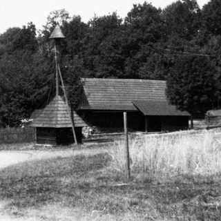 Rural road with wooden barns and two figures.
