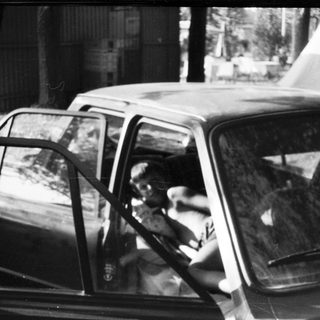 Two people in a parked vintage car.