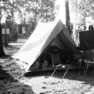Campsite with tent, car, and camping gear.
