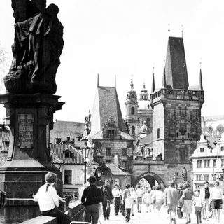 Historic Prague Charles Bridge with statues and pedestrians.