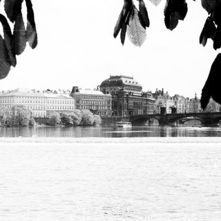 Historic buildings by river with bridge.