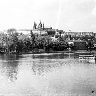 Historic castle complex by river with boats.